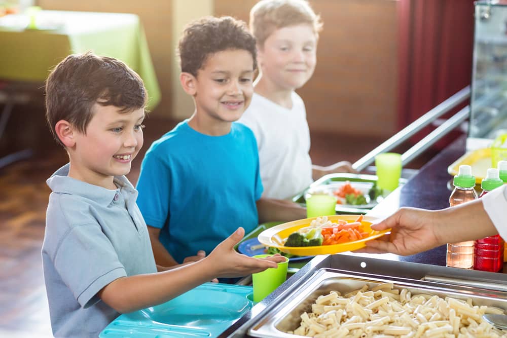 woman serving food to children queing up